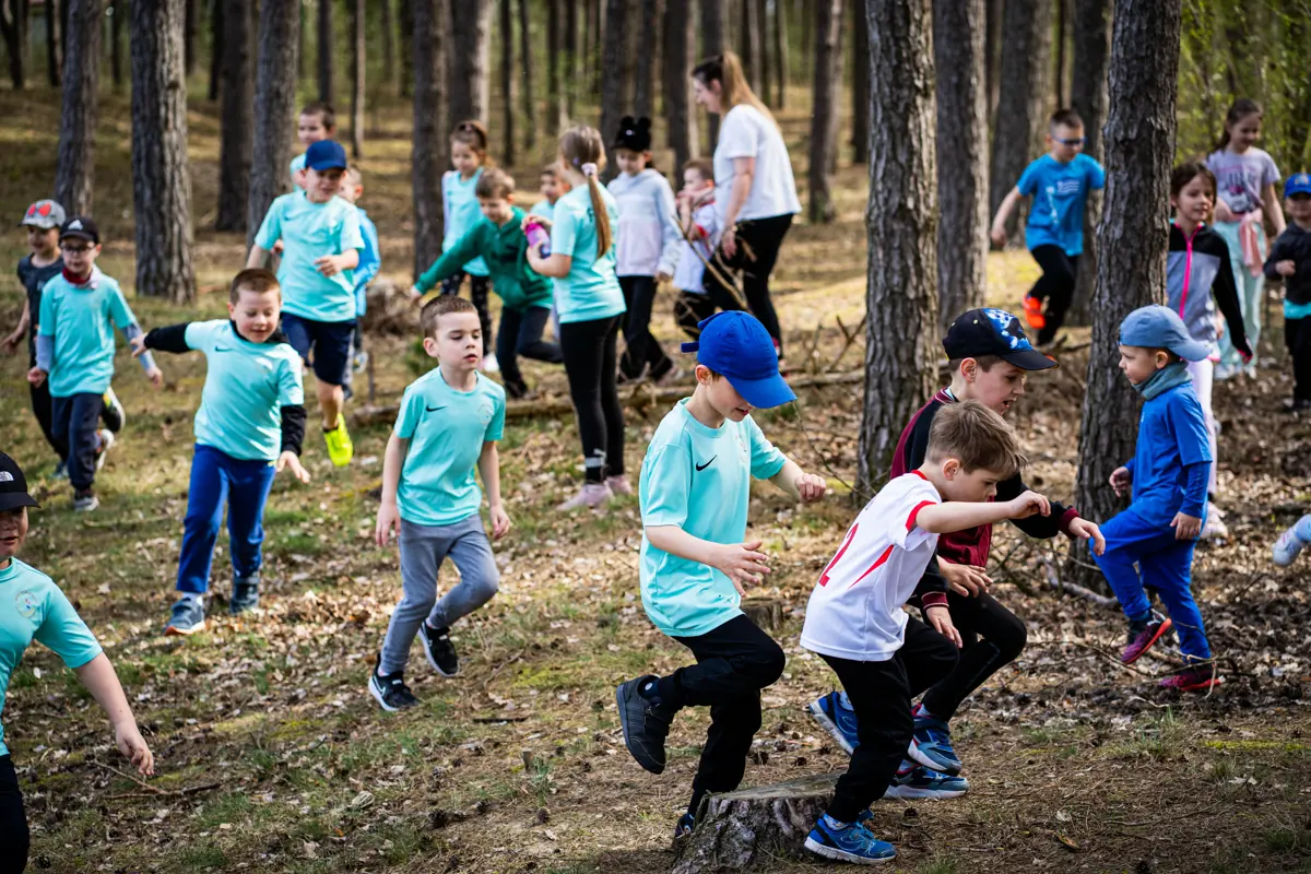 Dzieci biegną leśną ścieżką podczas gry terenowej w Karpicku