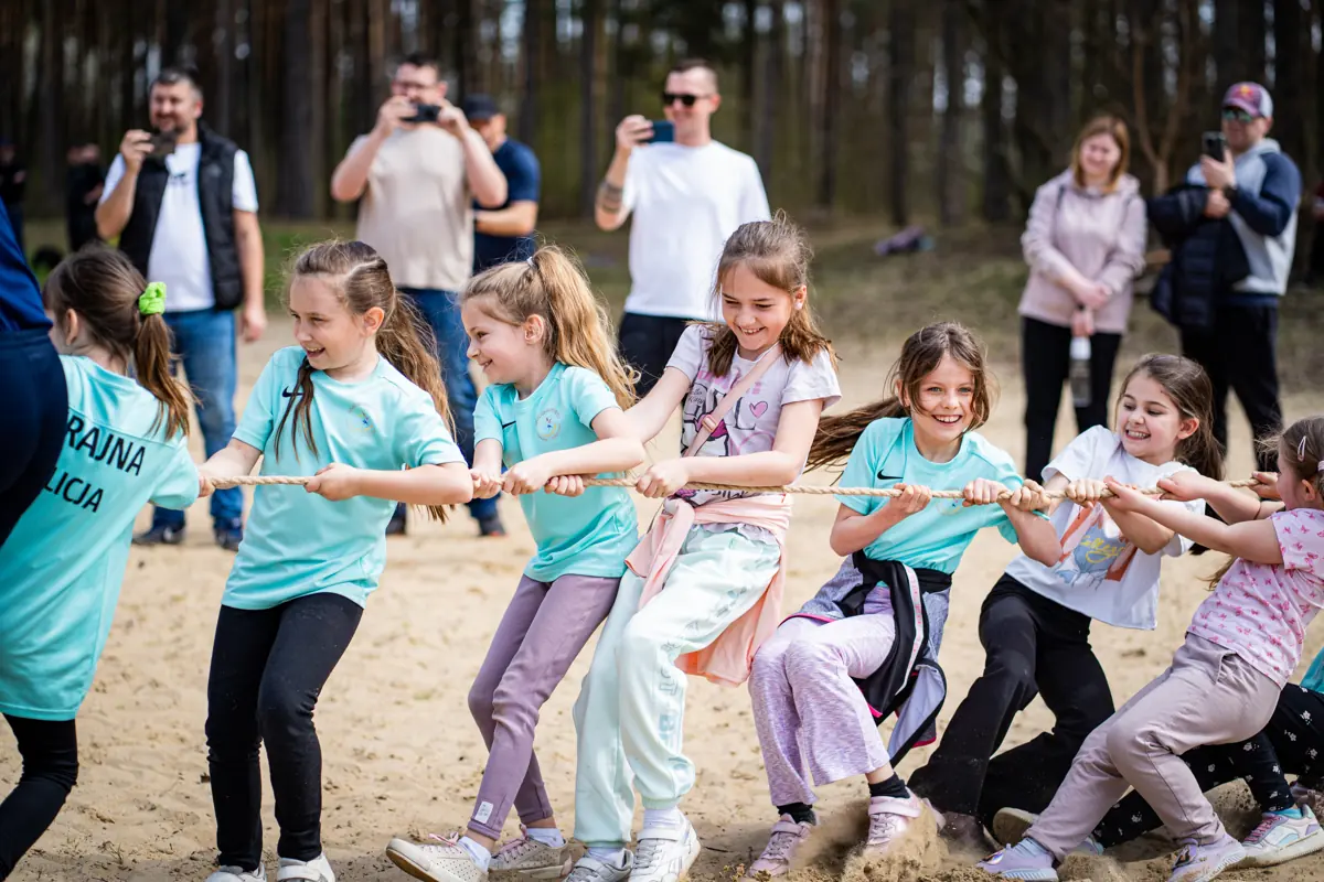 Dzieci przeciągają linę na piasku podczas rodzinnej gry terenowej