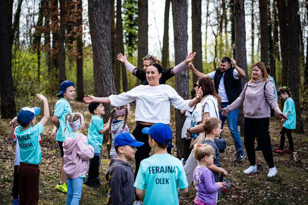 Dzieci i rodzice bawią się w kole podczas gry terenowej