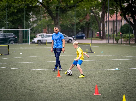 Trener prowadzi ćwiczenie z jednym zawodnikiem na boisku