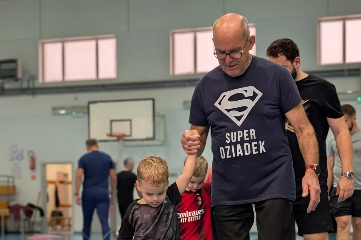Dziadek w koszulce z napisem Super Dziadek prowadzi wnuka przez tor przeszkód