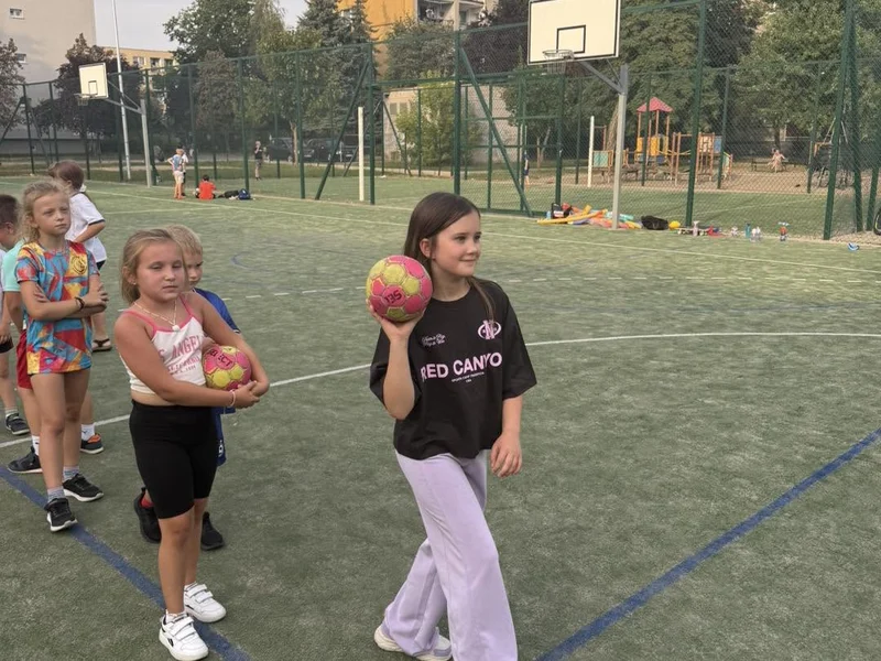 Dziewczynki z piłkami na boisku trawiastym podczas zajęć