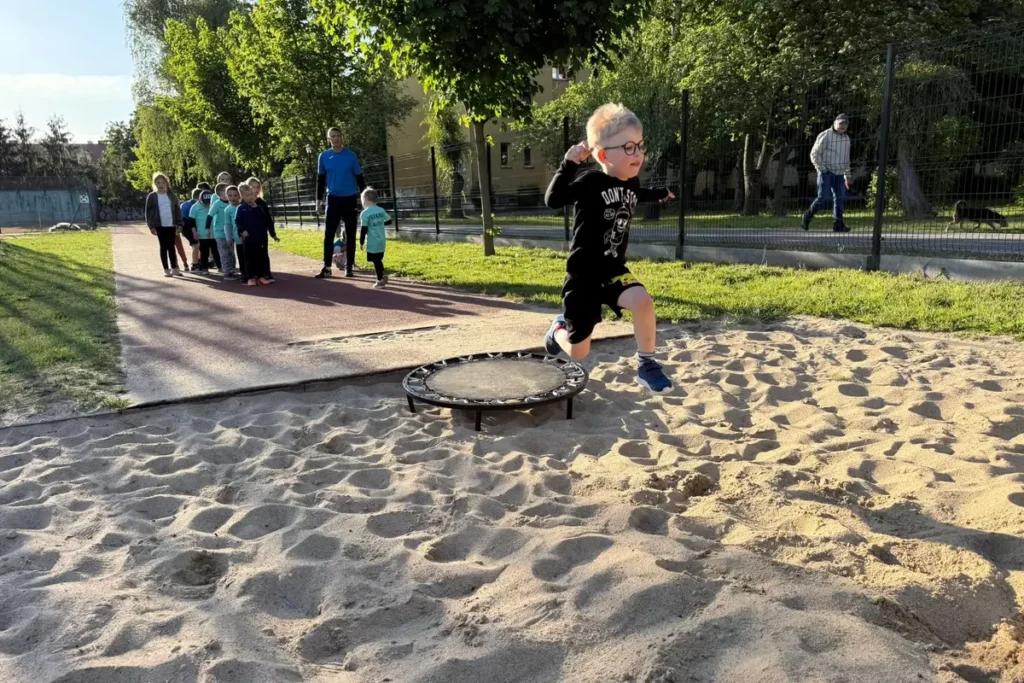 Chłopiec biegnie po piasku na świeżym powietrzu podczas zajęć sportowych