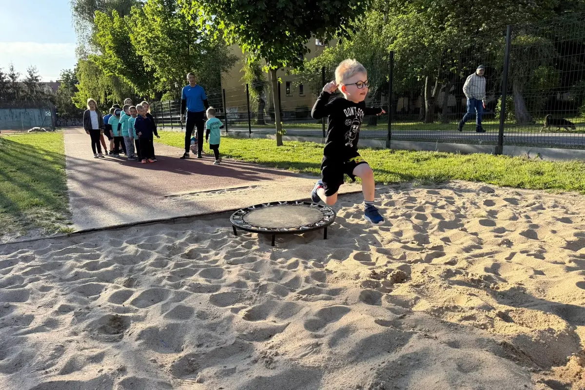 Chłopiec biegnie po piasku na świeżym powietrzu podczas zajęć sportowych