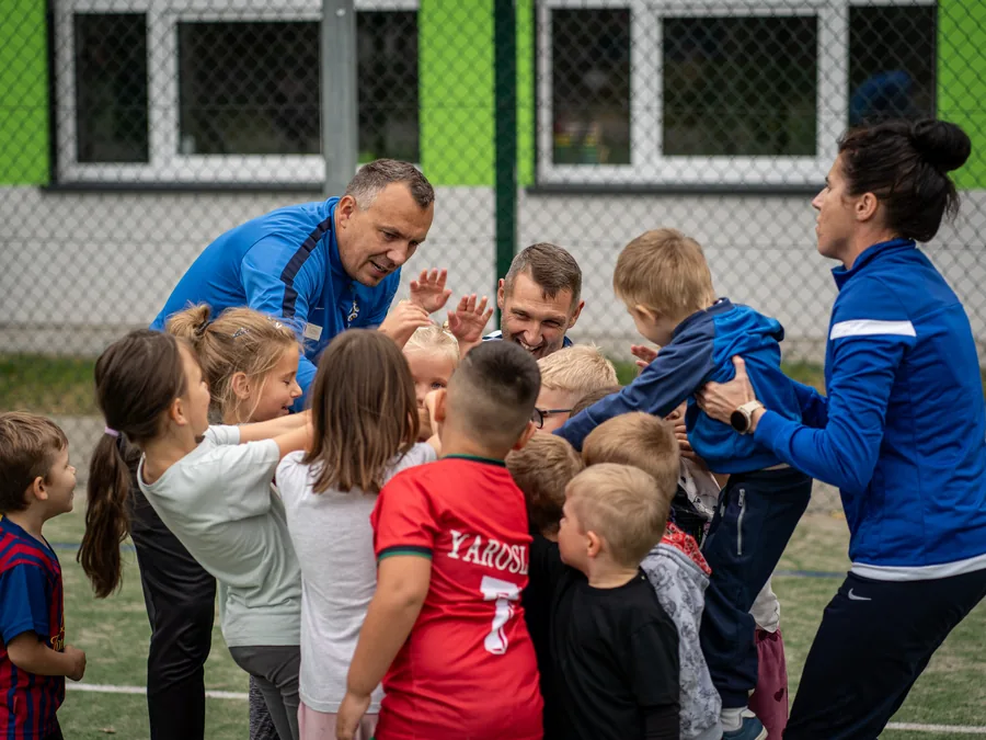 Trenerzy Ferajny w kręgu roześmianych dzieci po zakończonym treningu